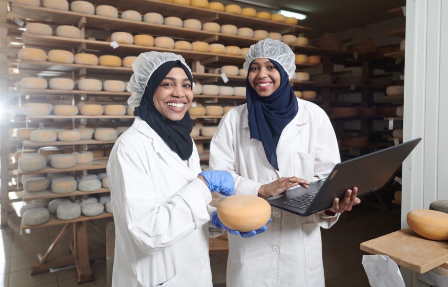 To kvinder med hovedtørklæder arbejder på ostefabrik